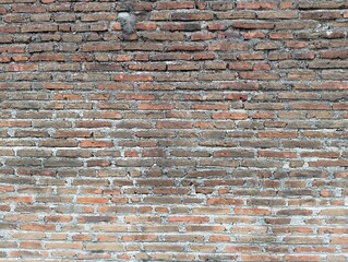 A close-up view of an old red brick wall with a rustic texture. Ideal for backgrounds, architectural themes, or historical context.
