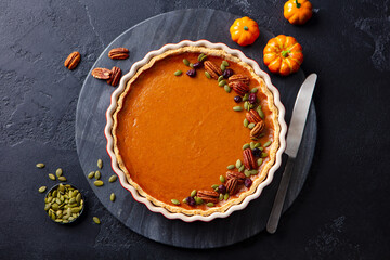 Pumpkin pie, tart in baking dish. Black background. Top view.