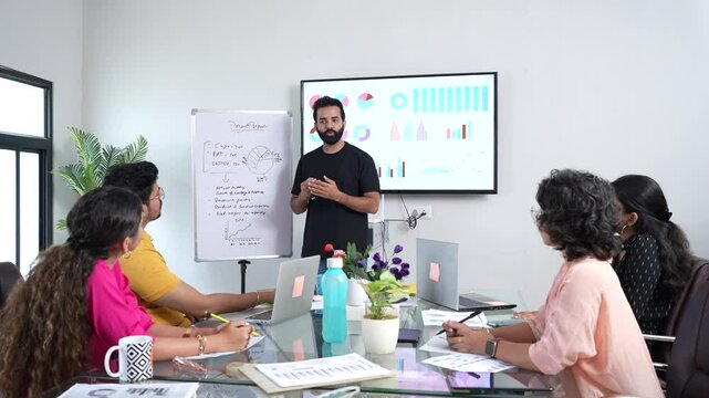 young indian man present business financial data on whiteboard at the workplace to colleagues for a start-up project. sales, analysis and strategy concepts.