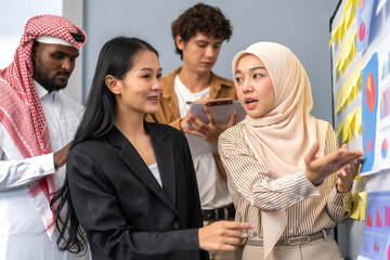 Diverse business team collaborating on project planning with charts and sticky notes on whiteboard, teamwork and brainstorming session in office, young professionals in modern business environment