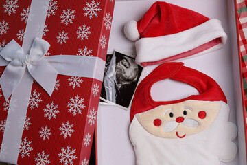 Santa Clause costume hat set for baby and ultrasound screening image on a red gift box