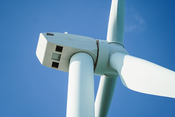 A large wind turbine for generating electricity using the force of the wind installed in an agricultural field against a blue sky. © arneaw