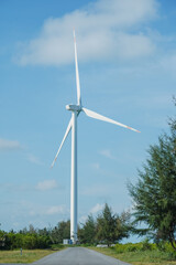 Fototapeta premium A large wind turbine for generating electricity using the force of the wind installed in an agricultural field against a blue sky.