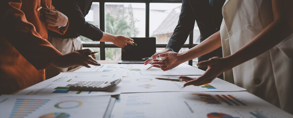Group of business men and women meeting, pointing at graphs, charts Work together on the table to...