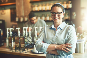 Crossed arms, woman and portrait of waitress in coffee shop with confidence for food industry. Happy, pride and server from London with smile for hospitality career in cafe with professional service.