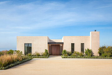Fototapeta premium Modern minimalist home with lush landscaping under a clear blue sky in a tranquil setting