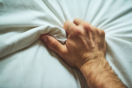 Hand, sheet and man with pleasure on bed in home for grip with ecstasy, climax or excitement. Erotic, sexual and closeup of male person clutching duvet in hotel room for passionate sensual feeling.
