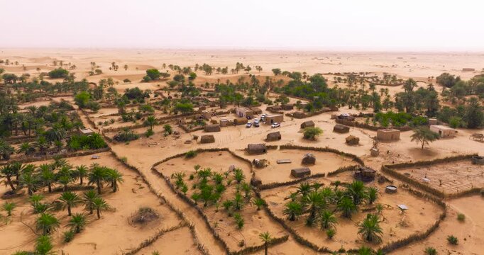 Straw Huts And Palm Tree Grove At The Tanouchert Oasis In Mauritania. - aerial shot