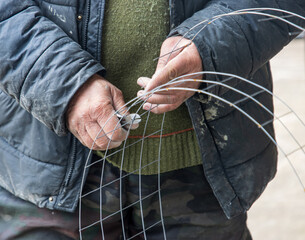 A man is holding a pair of wire cutters and is about to cut a piece of wire