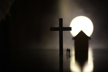 Naklejka premium Silhouetted Figures near Cross and House at Sunset - Spirituality and Home Concept Image