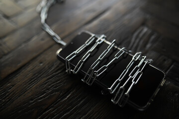 Smartphone Wrapped in Chains on Dark Wooden Surface Representing Security and Restrictions