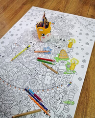 Coloring with pencils a large poster of a Christmas tree coloring page. Entertainment for the Christmas holidays