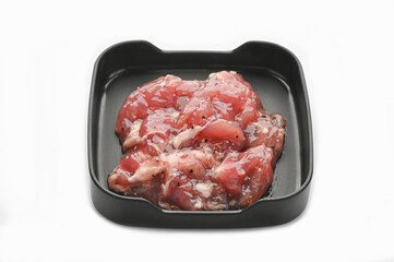 Marinated tender pork with black pepper in black tray on white background.