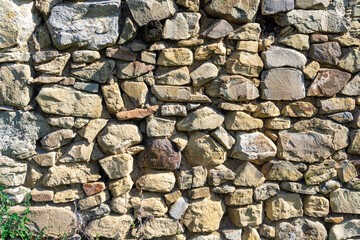 Wall of stones of different sizes, gray and light brown color. Dry masonry without cement