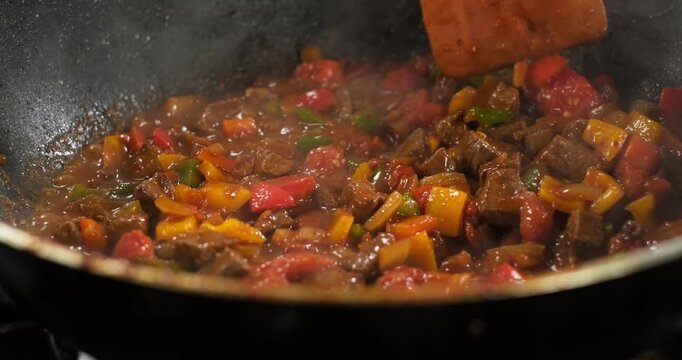 Close-up chef preparing meat and vegetables on a stove, stir meat colorful bell peppers onion frying in a pan. Healthy food preparation