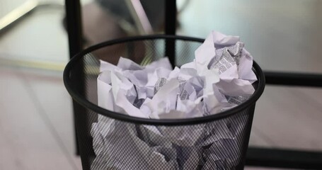 Crumpled paper is thrown into trash can in office