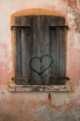 Un cuore dipinto con vernice verde su una finestra chiusa nel borgo di Erto nei pressi della diga del Vajont 
