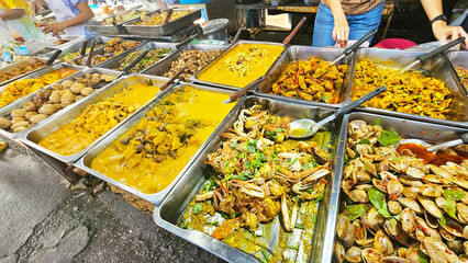 Delicious Street Food Market: A vibrant array of Thai curries and seafood dishes in gleaming metal trays, inviting you to experience the exotic flavors of a bustling Asian night market. 