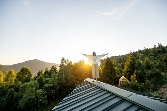 A woman walks on a rooftop as the sun rises over the mountains, embracing the peaceful solitude and beauty of nature. Perfect moment of calm and reflection