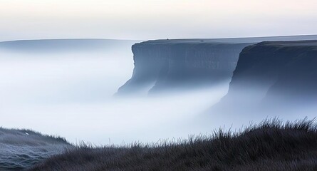 Misty landscape with cliffs and a lone figure on a serene morning.