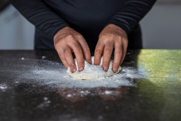 Close-up of man's hands kneading dough with flour
