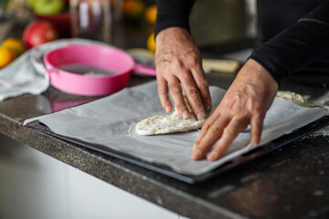 Close-up of man's hands shaping dough on parchment paper