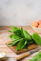 Prepared ingredients for cooking wild garlic and egg salad on a wooden background. The use of wild plants for food