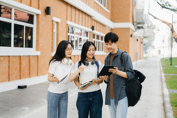 Young Asian college students and a female student group work at the campus park