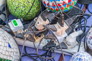 Old and damaged electric adapter power plug has many appliances are plugged outlet socket concept...