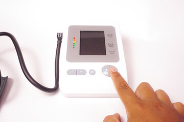 A man is pressing the start button on a digital blood pressure monitor.