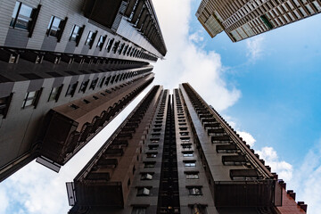 low angle back view of a skyscraper against sky and cloud background