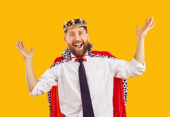Happy business man in king costume. Funny bearded man in office shirt, tie, plastic golden crown and red royal cape does ta da gesture and looks at camera with cheerful joyful smiling face expression