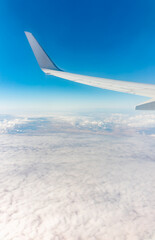 View from the airplane window at a beautiful cloudy sky and the airplane wing