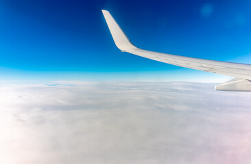 View from the airplane window at a beautiful cloudy sky and the airplane wing