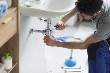 Professional plumber checking a sink drain