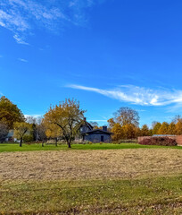 Obraz premium Autumn Countryside with Blue Sky and Rustic House. High quality photo