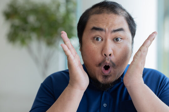 Excited happy thrilled Asian middle-aged man looking at you with surprise uh, oh expression