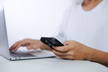 Middle-aged man in white shirt using laptop and smartphone on white background