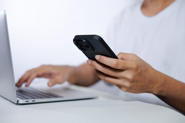 Middle-aged man in white shirt using laptop and smartphone on white background