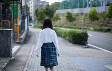 秋の昼の住宅街で歩くひとりの小学生の女の子の姿