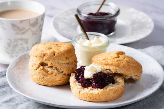 Milk tea with homemade scone 1 -  white marble backbround 1 - jam and cream on the scone 2