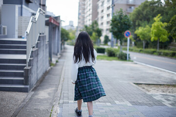 秋の昼の住宅街で歩くひとりの小学生の女の子の姿