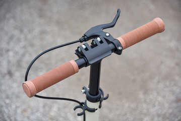 Scooter steering wheel with hand brake and beige rubber grips.