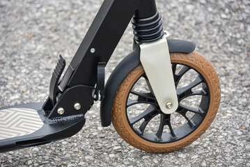 Front wheel of a scooter on asphalt. Close-up.