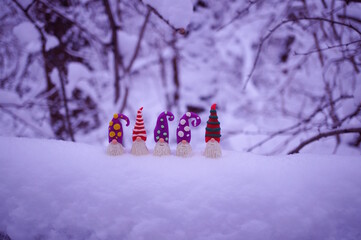 Toy dwarfs made of plasticine on a background of snow. Winter evening.