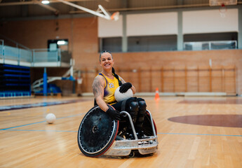 Happy disabled athlete sitting with sports ball in wheelchair