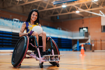 Happy disabled rugby player sitting with sports ball in wheelchair