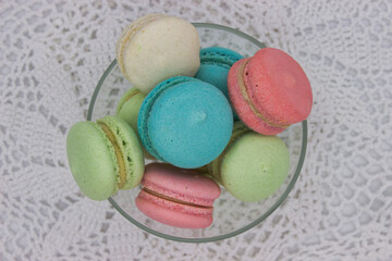 Top view of colorful macarons in a glass bowl on lace