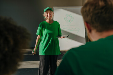 Smiling activist holding tablet PC near flipchart and having discussion in apartment