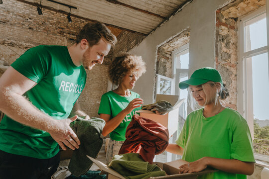 Smiling activists putting garments in donation boxes at apartment